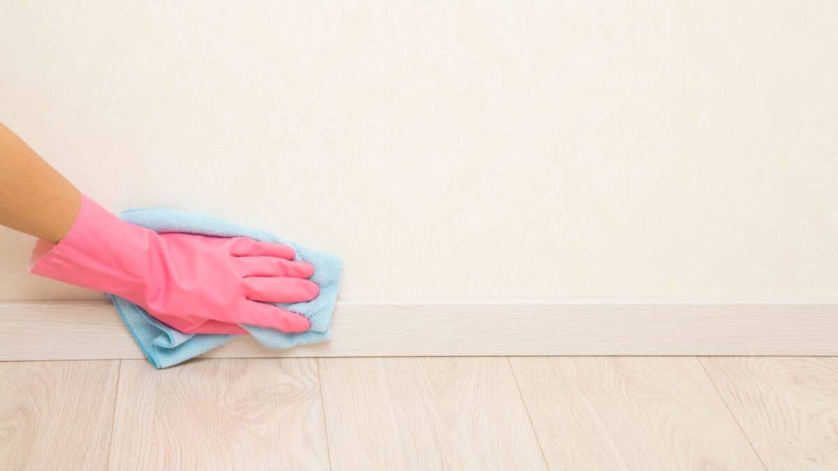 Personne nettoyant des plinthes avec un chiffon