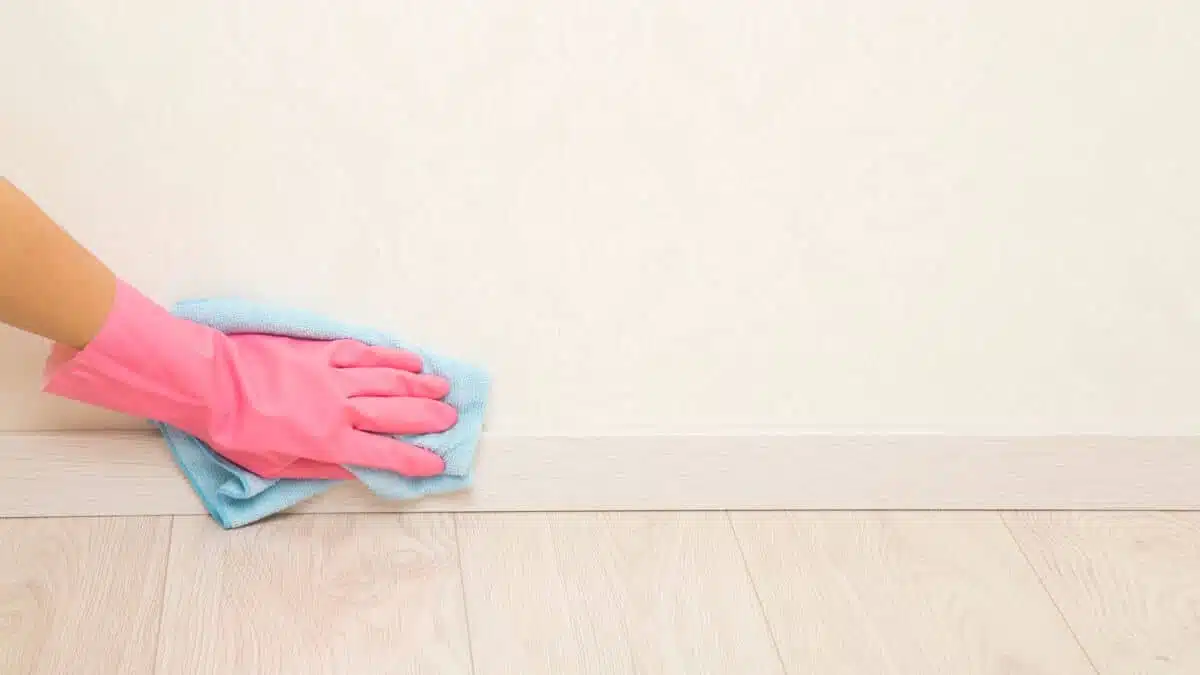 Personne nettoyant des plinthes avec un chiffon