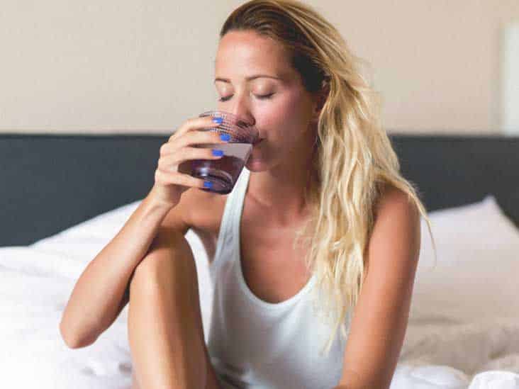 Femme buvant un verre d'eau au réveil
