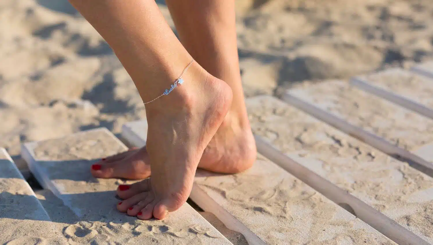 Femme portant un bracelet de cheville pieds nus sur la plage