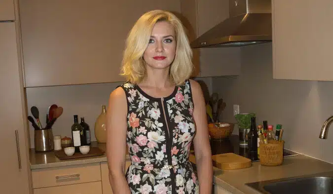 Une femme regarde par l'entrebâillement d'une porte d'entrée, illustrant une confrontation inattendue.