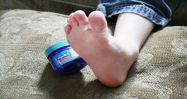 Personne massant ses pieds avec du VapoRub avant de dormir