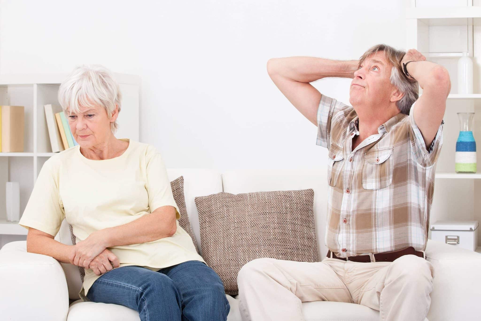 Photo d'un homme et d'une femme d'âge mûr se tenant les mains, regardant au loin avec une expression mélancolique.