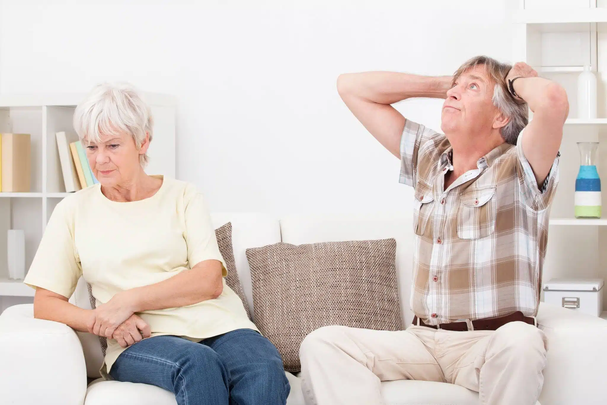 Photo d'un homme et d'une femme d'âge mûr se tenant les mains, regardant au loin avec une expression mélancolique.