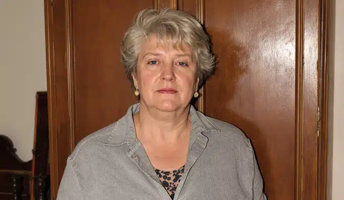 Vieilles photographies en noir et blanc éparpillées sur une table en bois, évoquant la recherche généalogique