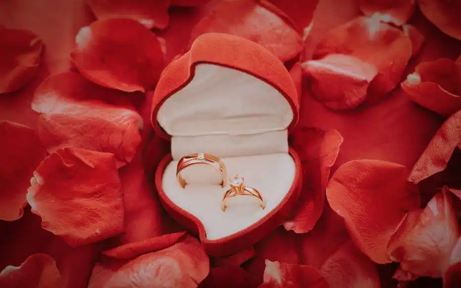 Un homme à genoux tend un écrin à une femme émue, dans une église