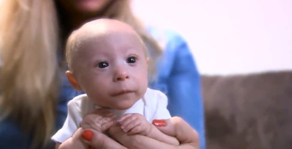 Mathieu, souriant, jouant sur un tapis avec ses frères