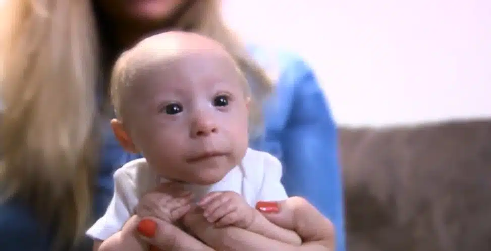 Mathieu, souriant, jouant sur un tapis avec ses frères