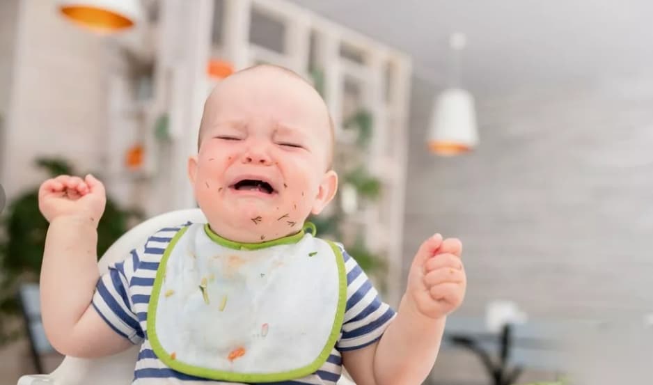 Une femme semblant stressée dans un avion, avec un bébé pleurant.