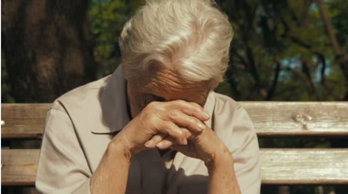 Un adolescent souriant s'adressant à une grand-mère et son bébé dans un avion.