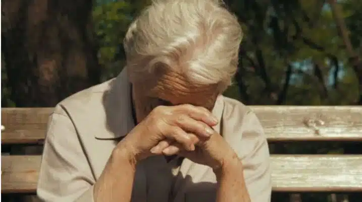 Un adolescent souriant s'adressant à une grand-mère et son bébé dans un avion.