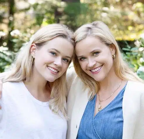 Reese Witherspoon tenant un livre, souriante, lors d'une séance de son club de lecture