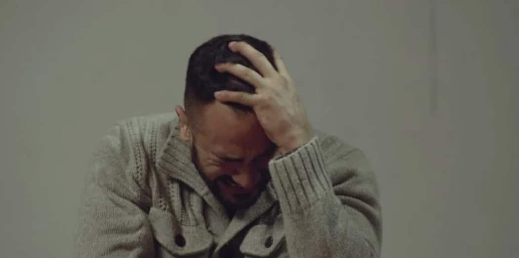 Cérémonie sur une scène, un adolescent remettant une médaille à un homme ému