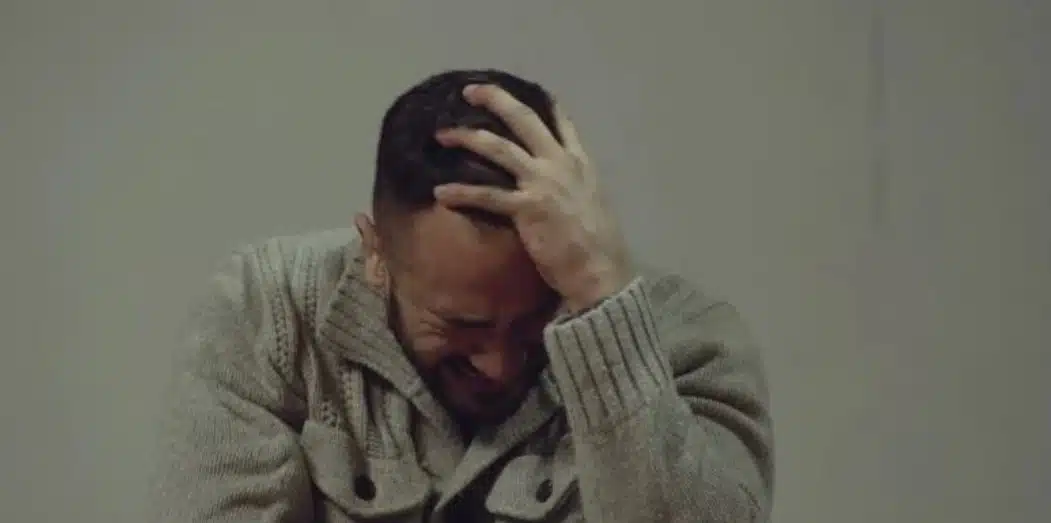 Cérémonie sur une scène, un adolescent remettant une médaille à un homme ému