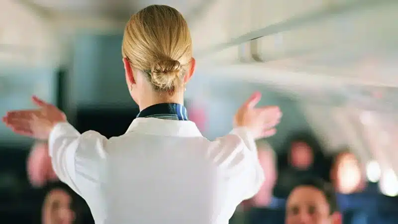Hôtesse de l'air en uniforme dans la cabine d'un avion