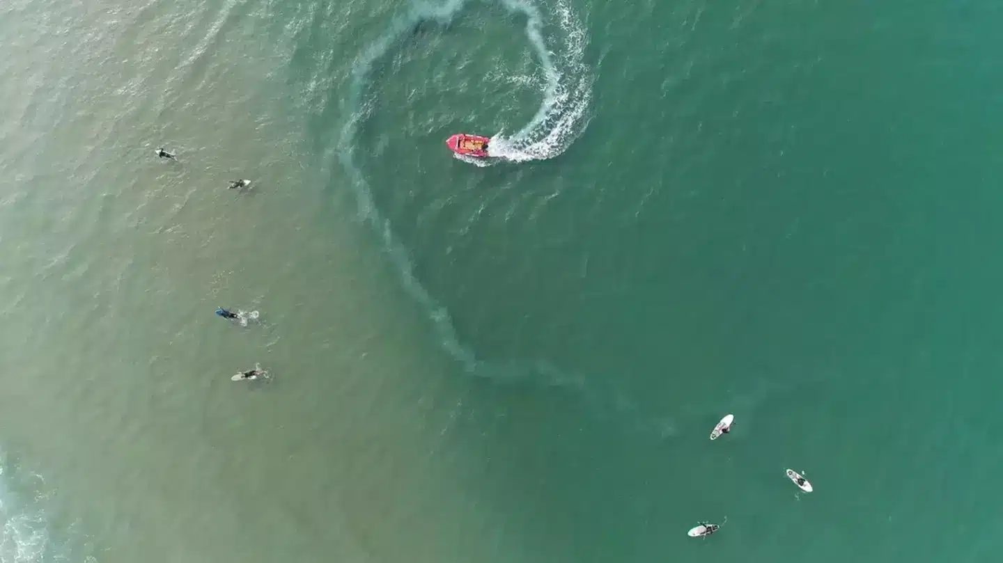 Photographie aérienne d'un bateau et de surfeurs dans l'océan