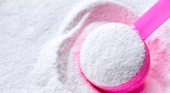 Cuillère doseuse au-dessus d'un paquet de lessive en poudre