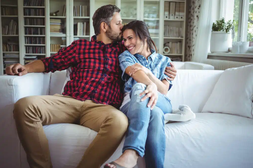 Couple assis sur un canapé s'échangeant un baiser