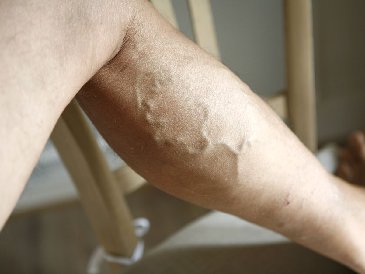 Femme souriante, les jambes surélevées sur un coussin, lisant un livre