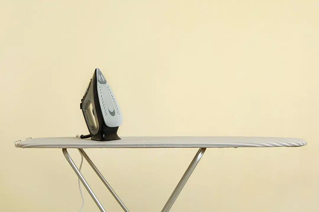 Fer à repasser moderne posé sur une planche à repasser