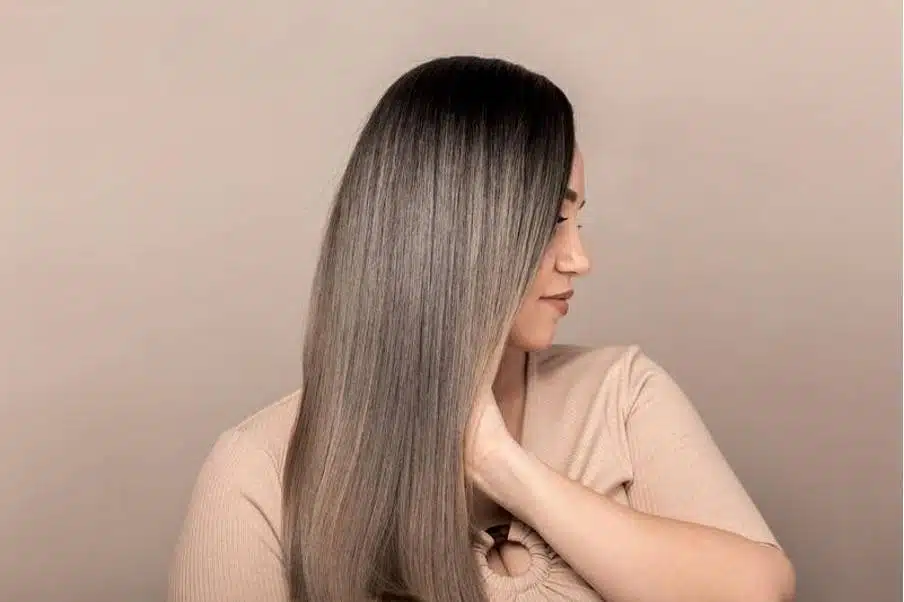 Femme aux cheveux lisses et brillants, tenant une feuille verte