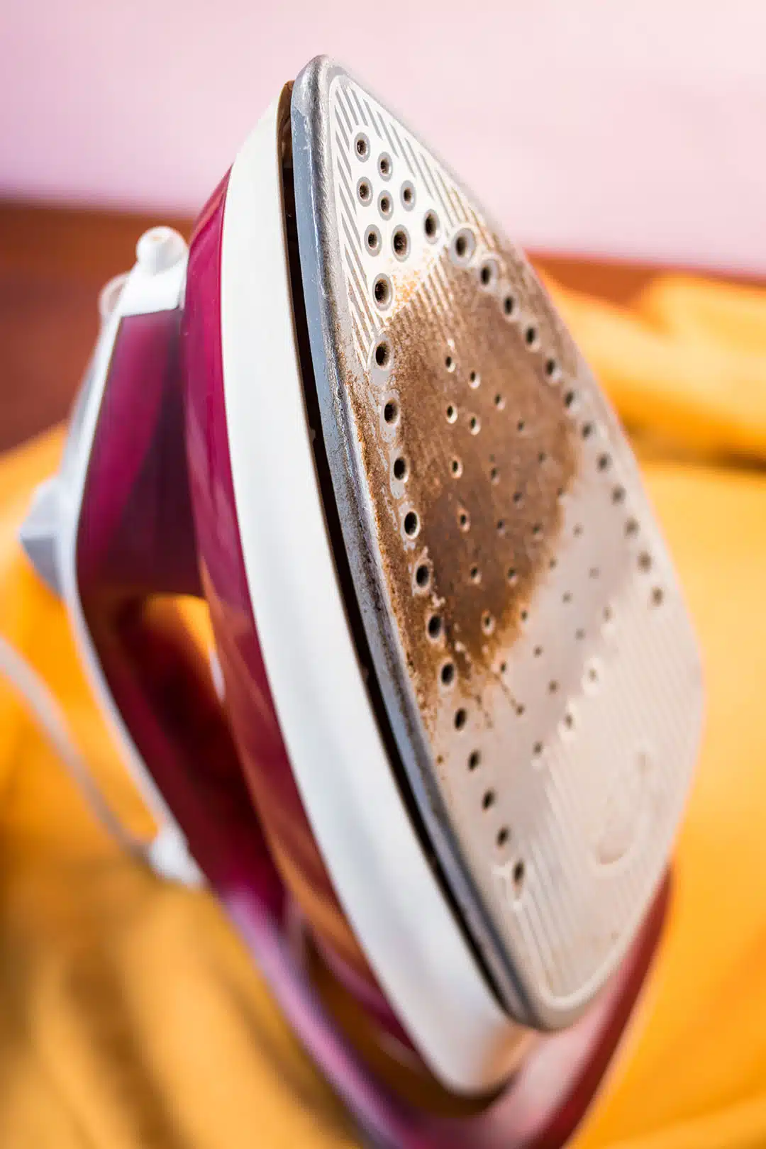 Fer à vapeur posé sur une planche à repasser avec un tissu jaune