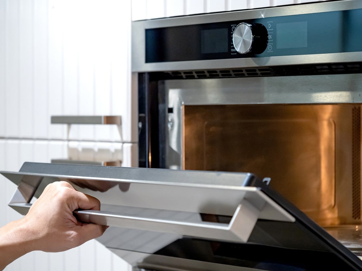 Personne nettoyant un four avec une éponge